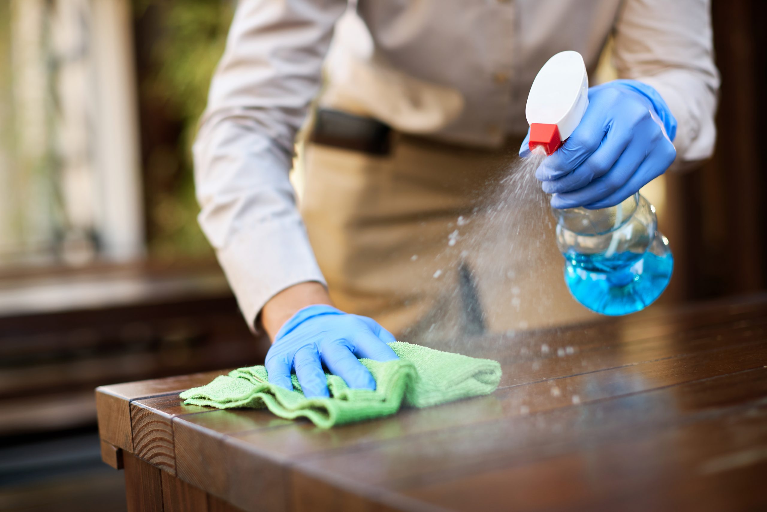 Close-up of waitress disinfecting tables at outdoor cafe